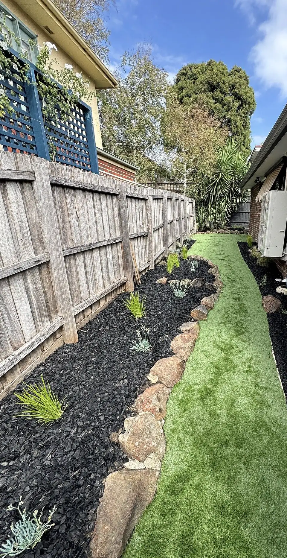 Artificial turf path winding between mulched garden beds with rock edging, installed by GardenScaping